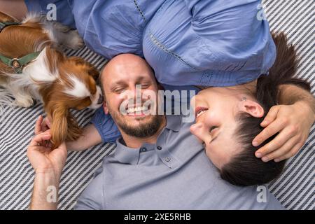 Eine glückliche Familie erwartet ein Kind. Ein Mann und seine schwangere Frau mit Hund liegen auf dem Gras in einem Stadtpark. Blick von oben. Schwangerschaft, erwartet ein c Stockfoto