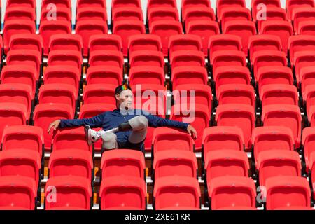 Behinderte Athleten in einem blauen Shirt sitzen auf den roten Sitzen im Stadion und bereiten sich auf das Lauftraining vor. Stockfoto