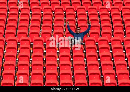 Behinderte Athleten in einem blauen Shirt sitzen auf den roten Sitzen im Stadion und bereiten sich auf das Lauftraining vor. Stockfoto