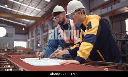 Team von Ingenieuren und Architekten, die mit Blueprint am Werksstandort arbeiten. Es handelt sich um einen massiven neuen Standort für die Herstellung von Metallblechen wie Stockfoto