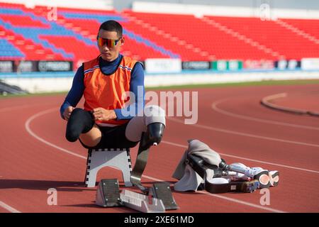 Behinderte Athleten bereiten sich in der Startposition vor, um auf der Stadionstrecke zu laufen Stockfoto