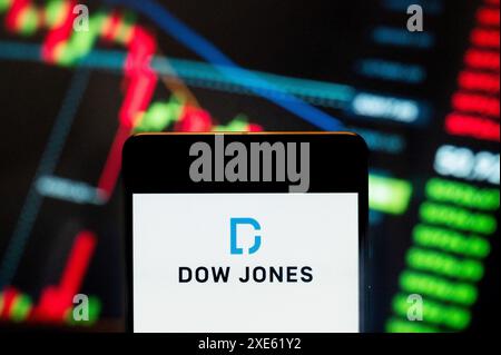 In dieser Fotoabbildung wird der amerikanische Aktienindex des 30 prominenten Unternehmens Dow Jones Industrial Average (DJIA)-Logos auf einem Smartphone mit einem wirtschaftlichen Börsenindex-Diagramm im Hintergrund angezeigt. Stockfoto