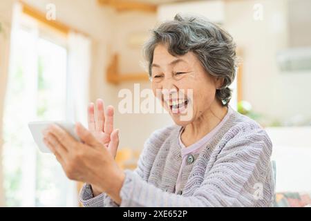 Eine ältere Frau, die Videoanrufe mit Enkeln zu Hause macht Stockfoto