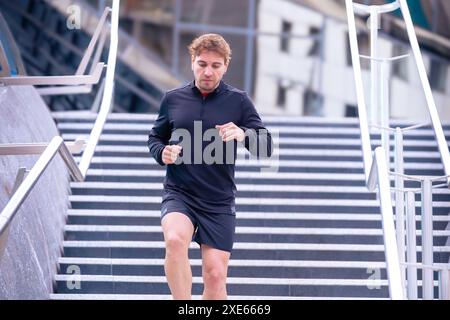 Athleten-Fitnesstraining, das Treppen hinunter läuft und dynamische Übungen im Freien macht. Stockfoto