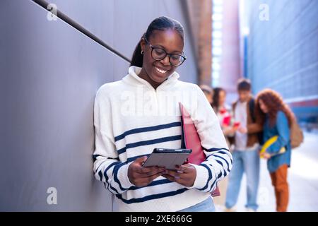 Junge afroamerikanische Frau, die im Internet surft, indem sie draußen ein Smartphone benutzt. Stockfoto