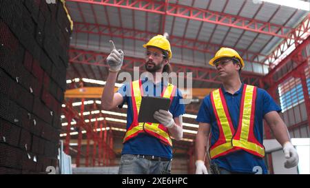 Lagerarbeiter in Schutzhelmen und Helmen, untersuchen und zählen Stahl im Lager. Stockfoto