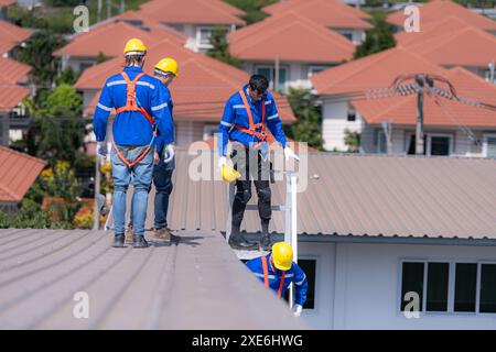 Nach der Installation und Überprüfung der Leistung der Solarzellen auf dem Fabrikdach installiert eine Gruppe von Ingenieuren diese Stockfoto