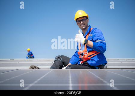 Techniker, der Solarpaneele repariert, ruhen in der sengenden Sonne auf einem Fabrikdach aus, das mit Solarpaneelen bedeckt ist, um Solarenergie zu erhalten. Stockfoto