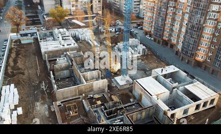 Eine Luftaufnahme einer Baustelle in einer Stadt. Ein großer Kran dominiert die Mitte des Rahmens und mehrere andere Baumaschinen Stockfoto