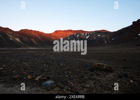 Roter Sonnenaufgang auf dem Kamm des Vulkans Tongariro und trockene Aschefelder im Vordergrund, Tongariro Nationalpark, UNESCO-Weltkulturerbe, Nordinsel Stockfoto