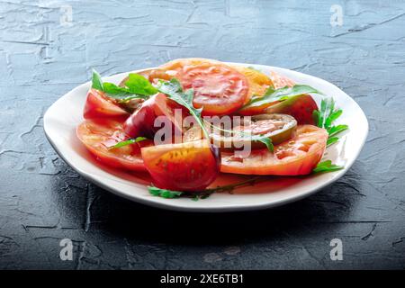 Frische Tomaten und Rucolasalat. Eine Vielzahl von Tomaten verschiedener Art Stockfoto