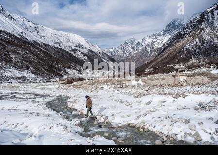 Männlicher Wanderer überquert einen gefrorenen Fluss in diesem schneebedeckten Höhental, Langtang Valley Trek, Himalaya, Nepal, Asien Copyright: CasparxSchlageter 1372- Stockfoto