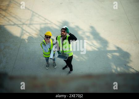 Blick von oben auf einer Baustelle diskutieren ein Ingenieur und Architekt auf einem Laptop. Stockfoto