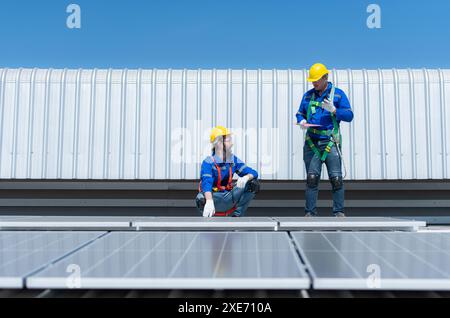 Beide Techniker installieren Solarpaneele auf dem Dach des Lagers, um Solarenergie in elektrische Energie für uns umzuwandeln Stockfoto