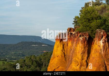 Blick auf ockerfarbene Klippen und die umliegende Landschaft, fotografiert von der historischen Stadt Roussillon, Provence im Süden Frankreichs. Stockfoto