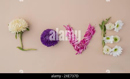 WORTLIEBE aus bunten Blumen auf femininem beigefarbenem Hintergrund. Konzept der Feiertagsfeiertage Valentinstag Frauen Tag Jäten Stockfoto