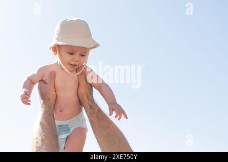Vater und Baby spielen unter einem sonnigen Himmel, ein aufbauender Moment. Väterliche Freude und kindliche Unschuld Stockfoto