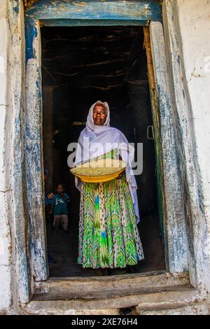 Freundlichen alten Frau mit einem Korb von Mais in einen Türrahmen in der Nähe von Keren, Eritrea, Afrika Stockfoto
