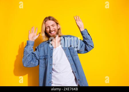 Foto-Porträt des hübschen jungen Mannes Tanz Diskothek tragen trendige Jeans Outfit isoliert auf gelbem Hintergrund Stockfoto