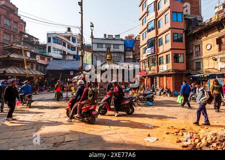 Viel Verkehr mit Motorrädern und Fußgängern auf einer staubigen Marktstraße, warmes Licht der morgendlichen Hauptverkehrszeit, Kathmandu, Nepal, Asien Stockfoto