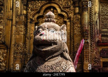 Nahaufnahme der Statue des Schutzlöwen vor der goldenen Mauer am Hindu-Tempel von Changu Narayan, Changunarayan, Kathmandu-Tal, Nepal Stockfoto