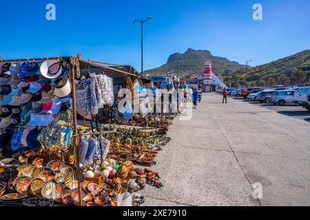 Blick auf Souvenirstände und farbenfrohe Bar und Leuchtturm in Hout Bay Harbour, Hout Bay, Kapstadt, Westkap, Südafrika, Afrika Stockfoto
