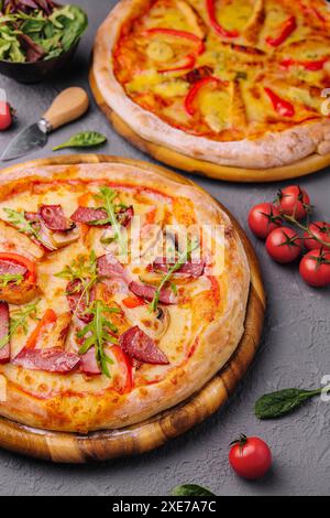 Gebackene runde Pizza mit Salami, Tomaten und Pilzen Stockfoto