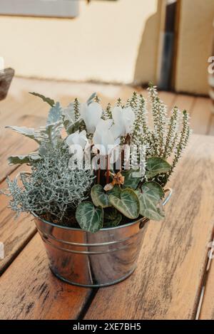 Blumen dekorativer Eimer Holztisch. Blütenzusammensetzung. Strauß von getrockneten Pflanzen, Blumen oder Blättern in einer kleinen Eimervase auf Stockfoto