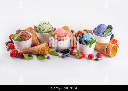 Buntes helles Eis auf Schüsseln, mit Waffelkegeln und Beeren, auf weißem Hintergrund. Verschiedene Eisportionen mit verschiedenen Aromen und frischen Zutaten Stockfoto