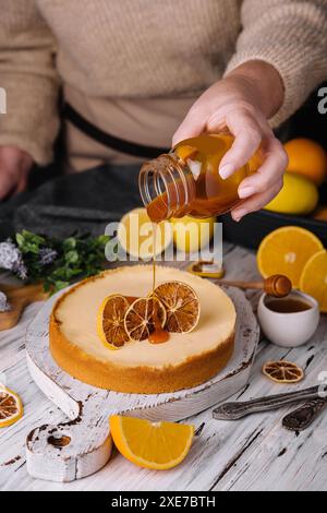 Frau, die Karamell auf Orangenkäsekuchen gießt Stockfoto