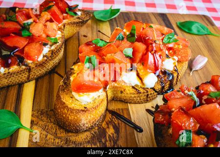 Italienische Bruschetta auf einem Holzteller serviert, dekoriert mit Basilikum. Stockfoto