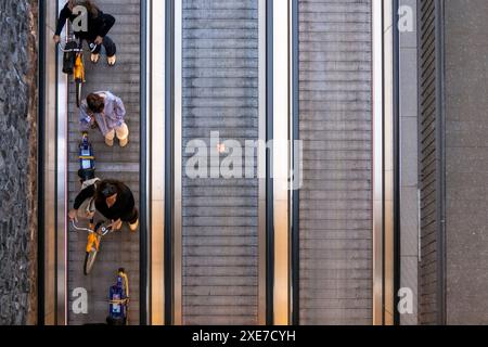 Menschen schieben ihre Fahrräder auf einen Reisenden, der die unterirdische Fahrradparkanlage vor dem Amsterdamer Hauptbahnhof in den Niederlanden betritt. Stockfoto