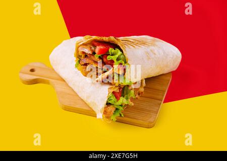 Shawarma mit Huhn, Tomaten und Salat auf einem Holzbrett Stockfoto