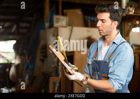 Der Zimmermann arbeitet in seiner Tischlerei. Das Sehvermögen wird verwendet, um die Genauigkeit zu gewährleisten. Stockfoto