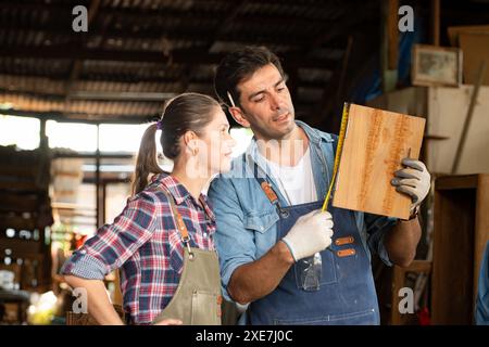 Zimmermann und seine Assistentin arbeiten zusammen in einer Tischlerei Stockfoto