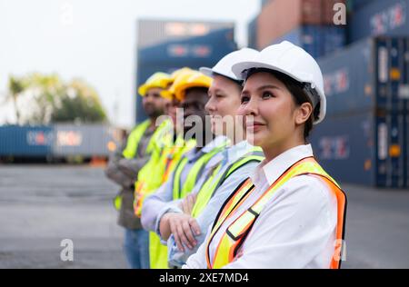 Gruppe von Arbeitnehmern mit Schutzhelm und reflektierender Weste, die vor Containern steht. Stockfoto