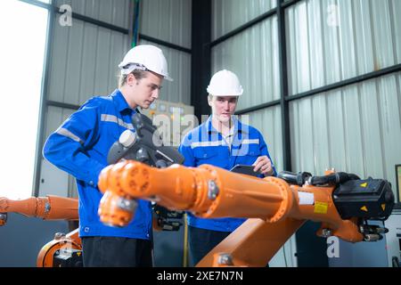Ingenieur und Techniker, die im Werk mit Roboterarm arbeiten. Industrie- und Ingenieurkonzept. Stockfoto