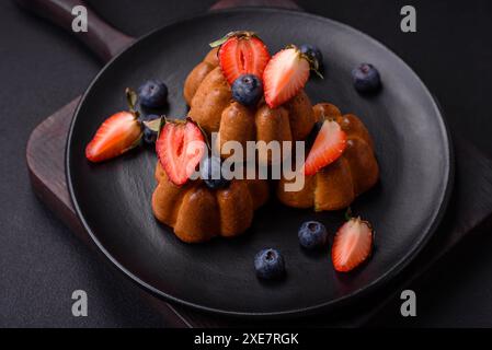 Köstliche Cupcakes oder Muffins mit Rosinen und Nüssen, Erdbeeren und Heidelbeeren Stockfoto