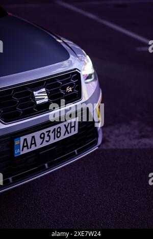 Silberner Ateca-SITZ, der bei Nacht violettes Licht reflektiert. Frontteil der Überkreuzung der kompakten Heckklappe – Stoßfänger, Kühlergrill und Motorhaube. Stockfoto