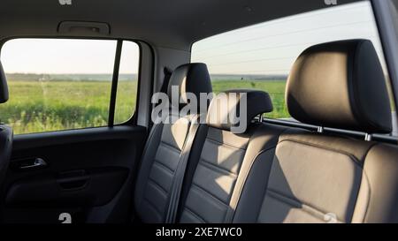 Hintere Sitzreihe in einem Pickup. Lederbank im Fahrzeug und grüne Wiese im Hintergrund. Stockfoto