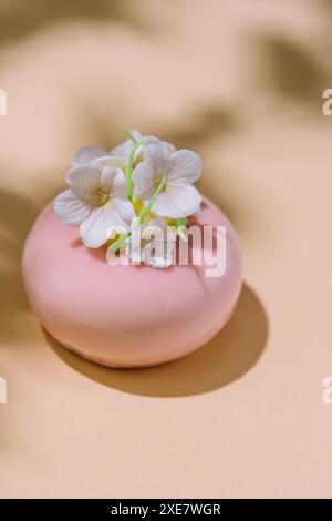 Rosafarbener Mousse-Kuchen mit Spiegelglasur, dekoriert mit Blumen Stockfoto