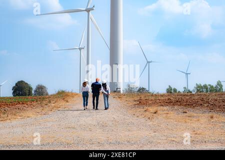 Rückansicht von Gruppeningenieuren, die in einer Windmühlenfarm auf Windkraftanlagen laufen. Stockfoto