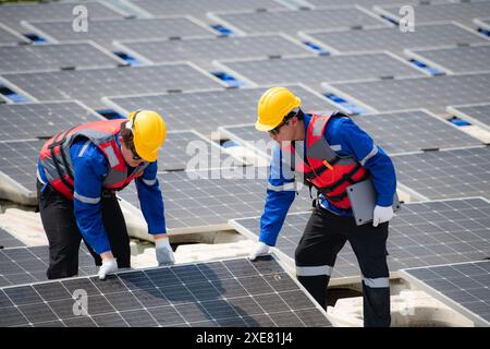 Photovoltaik-Ingenieure arbeiten an schwimmender Photovoltaik. Prüfen und reparieren Sie die auf dem Wasser schwimmenden Solarpaneele. Stockfoto