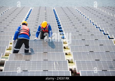 Photovoltaik-Ingenieure arbeiten an schwimmender Photovoltaik. Prüfen und reparieren Sie die auf dem Wasser schwimmenden Solarpaneele. Stockfoto