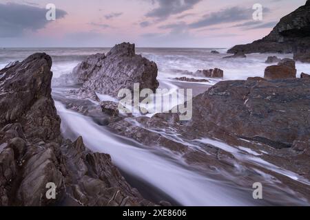 Wellen schweben um die zerklüfteten Felsen am Wildersmouth Beach, Ilfracombe, Devon, England. Winter (Januar) 2019. Stockfoto