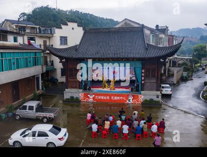 (240626) -- JINHUA, 26. Juni 2024 (Xinhua) -- ein Luftdrohnenfoto vom 25. Juni 2024 zeigt Dorfbewohner, die eine Wu-Opernaufführung im Dorf Zhengdian in Lipu, Stadt Jinhua, ostchinesische Provinz Zhejiang, beobachten. Wu Opera, auch bekannt als Jinhua Opera, hat eine mehr als 500-jährige Geschichte. Es wuchs zuerst in Jinhua und seinen umliegenden Gebieten an Popularität und wurde nach Wuzhou benannt, dem Namen Jinhua im alten China. Die lokalen Behörden des Bezirks Jindong in der Stadt Jinhua haben intensiv nach Möglichkeiten gesucht, um das Erbe und die Entwicklung der traditionellen Oper zu fördern. Stockfoto