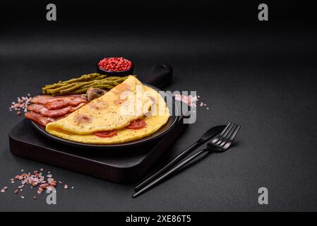 Köstliches frisches Omelett mit Kirschtomaten, Speck, Spargel und Gewürzen Stockfoto