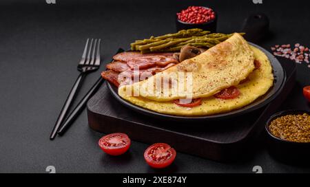 Köstliches frisches Omelett mit Kirschtomaten, Speck, Spargel und Gewürzen Stockfoto