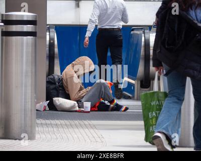 Obdachloser Bettler am Eingang der Liverpool Street Station in Central London, sitzt auf dem Boden und sammelt Geld Stockfoto