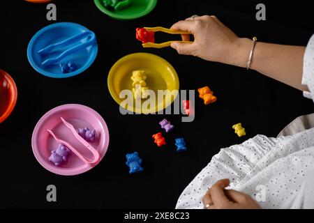 Entwicklung der Feinmotorik von Kindern mit Pinzetten und Kleinspielzeug Stockfoto